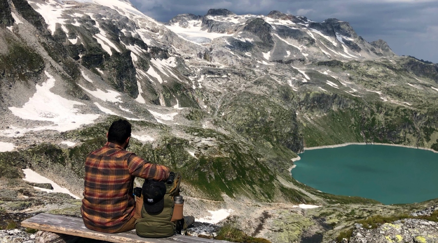Muž s batohem na lavičce na horách