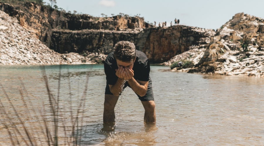Muž si myje obličej v řece