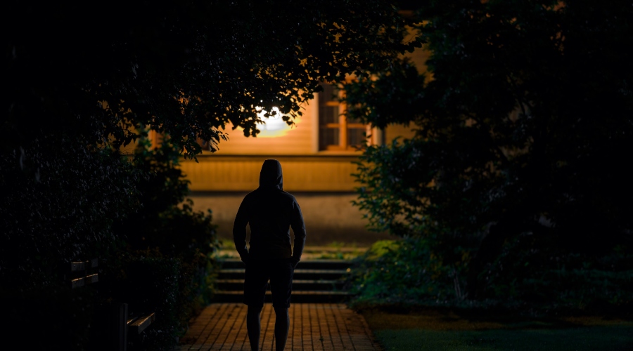 Muž stojí před domem s rozsvícenými světly