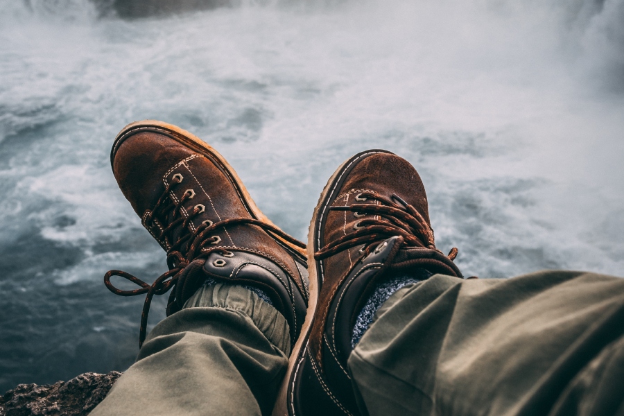 Muž sedí s botama nad hladinou moře