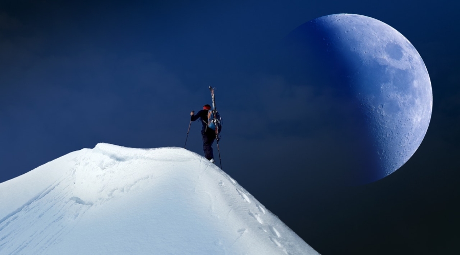 Muž na zasněžené hoře s měsícem v pozadí
