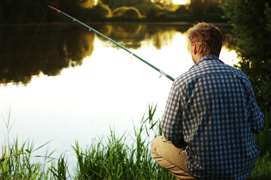 Rybář sedící a čekající na břehu řeky