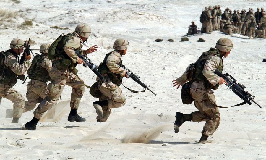 Skupina vojáků běžící pouští ve válce
