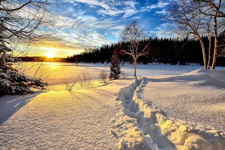 Vyšlapaná cesta ve hlubokém sněhu při západu slunce