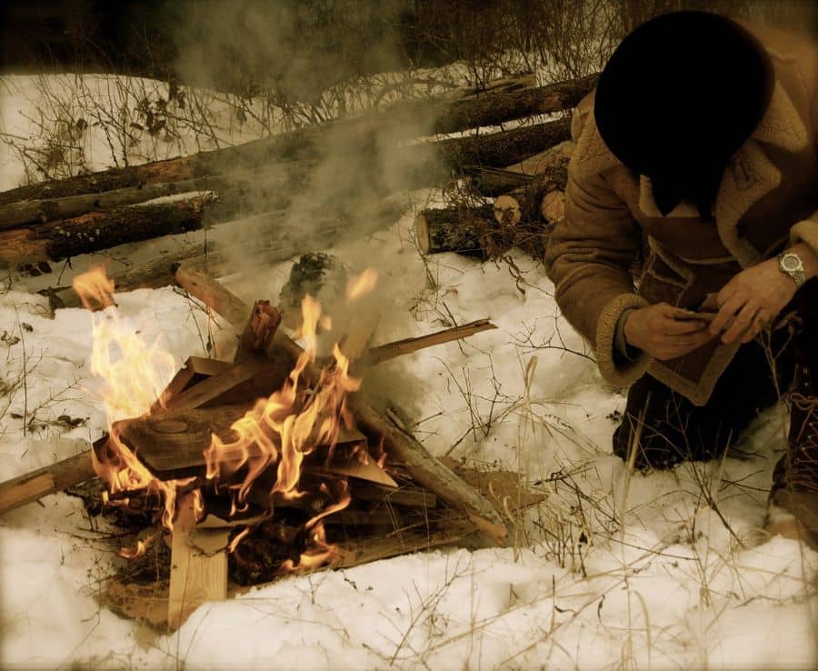 Muž rozdělává oheň na sněhu